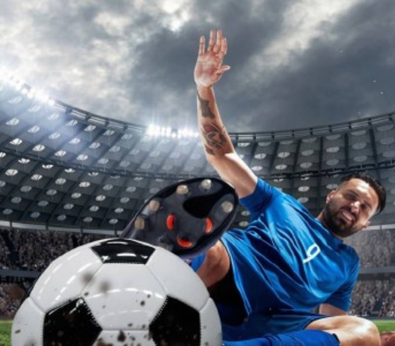 Football player in blue jersey tackling for the ball inside a large stadium