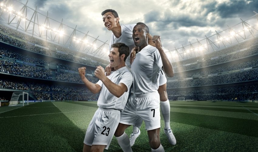 Joyful soccer players celebrating a win at center field in stadium