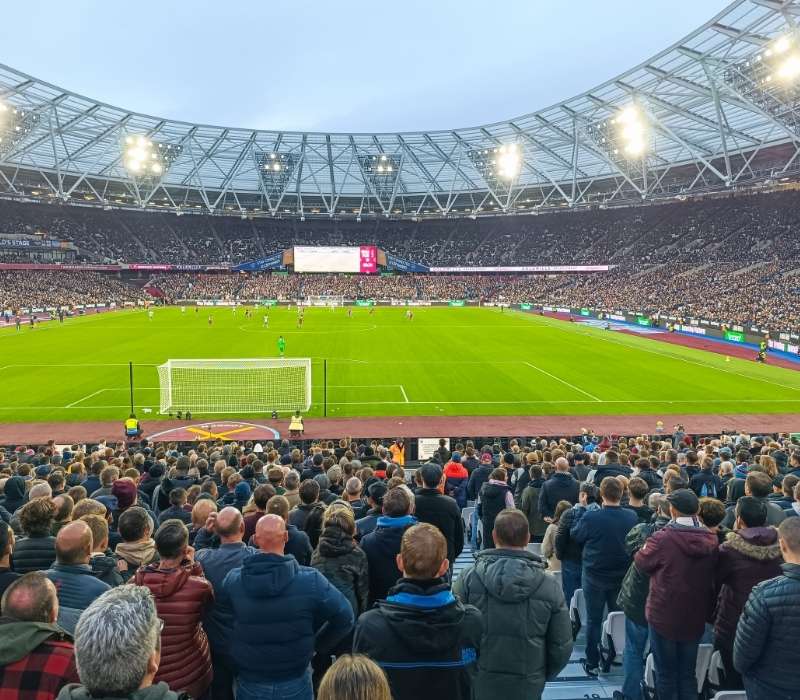 Spectators cheering during a football match at London Stadium, UK